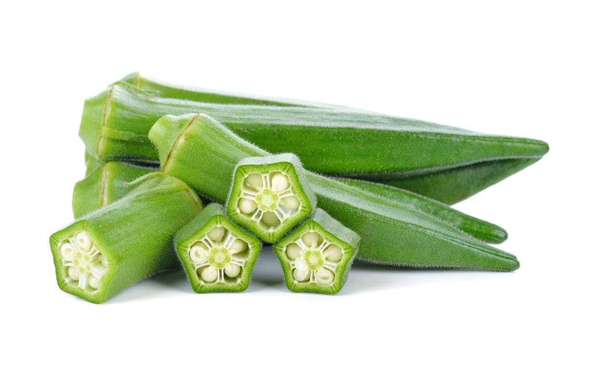 pile of okra on white background with on cut into pieces to display cross-section