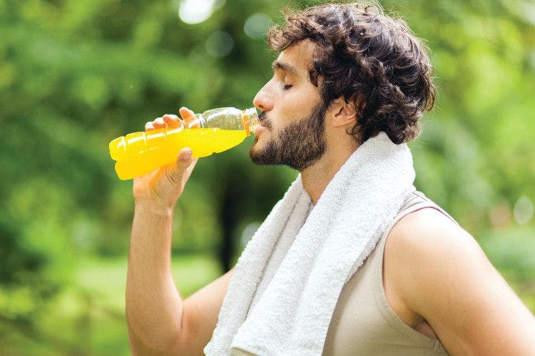 man drinking sports beverage with towel around his neck
