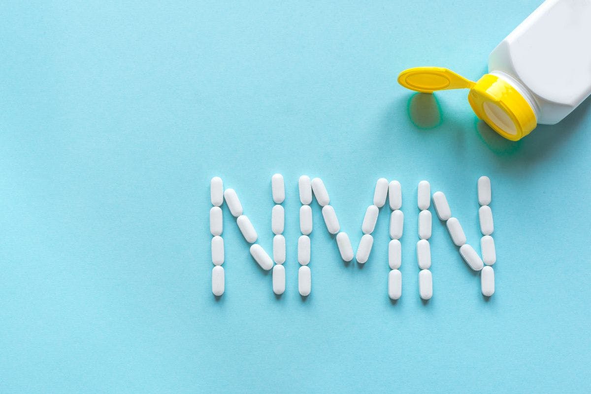 NMN spelled out in tablets with pill bottle in corner of frame. 