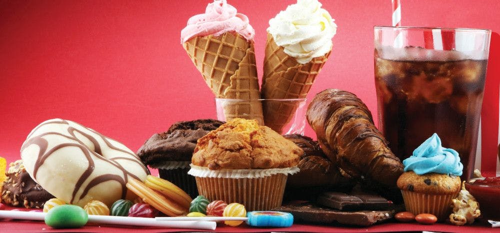 donuts, chocolates, muffins, ice cream, candy, and soda on red background