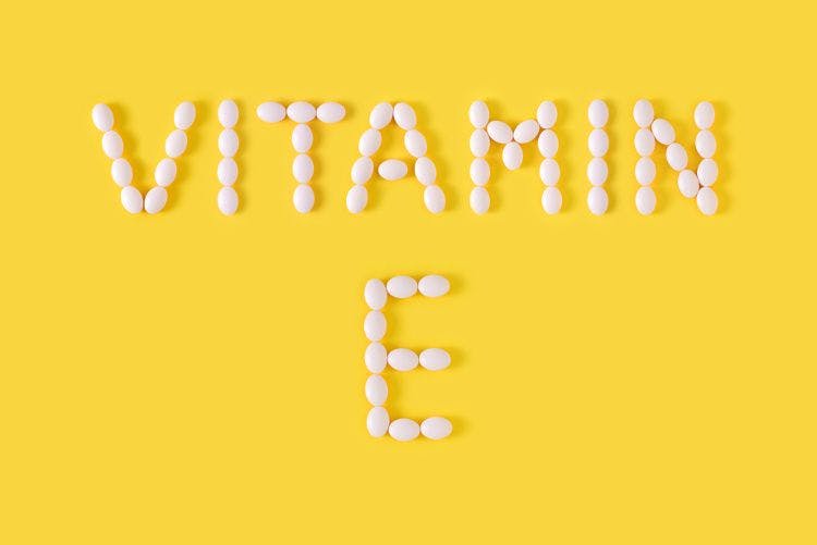 vitamin E spelled with pills on yellow background